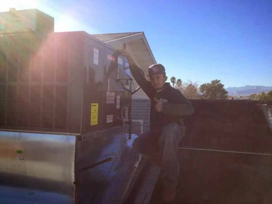 HVAC technician performing AC Tune-Up on a rooftop unit in Oronoko